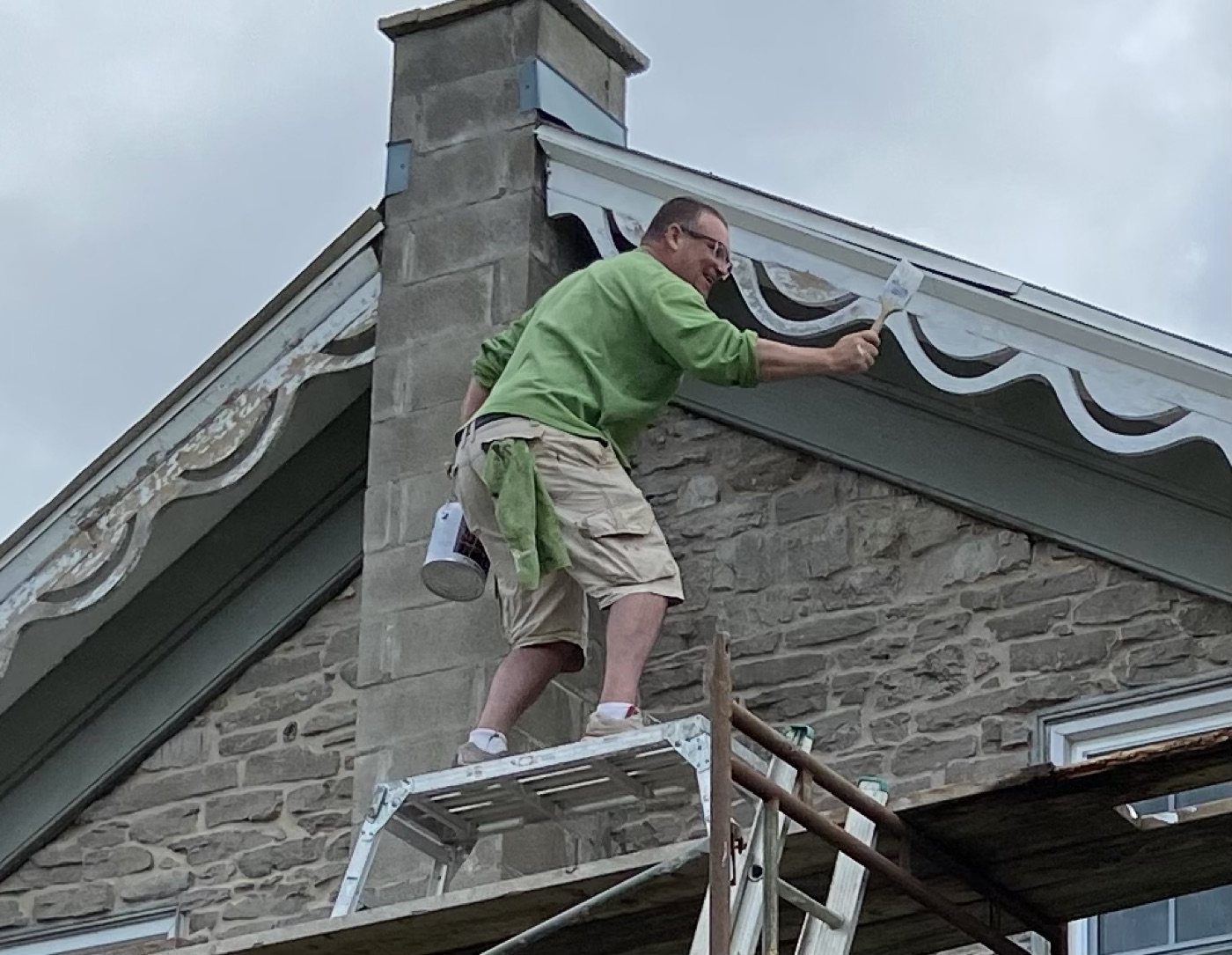Exterior trim painting in progress on a stone home